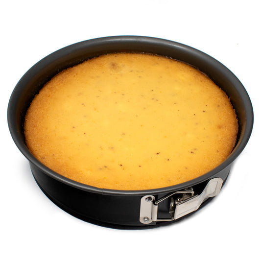 Golden baked cheesecake inside a black 10-inch springform pan with the silver latch visible along the front edge.