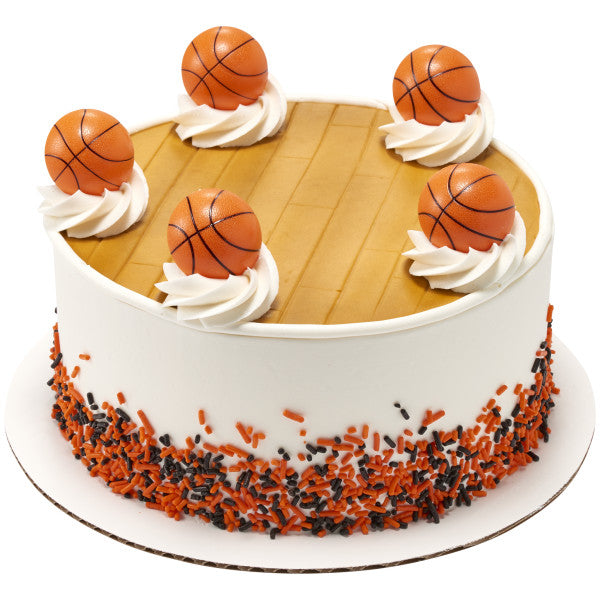 Round cake decorated with white frosting swirls and five 3D basketball rings on top, basketball court design in the center.