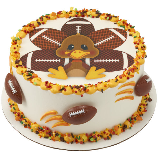 White frosted cake with turkey design and 3D football rings around the sides.