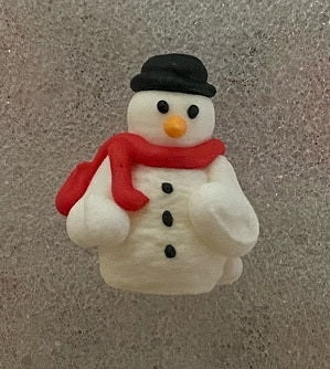 Standing 3D royal icing snowman decoration with a black hat, red scarf, orange nose, black eyes, and three black buttons.