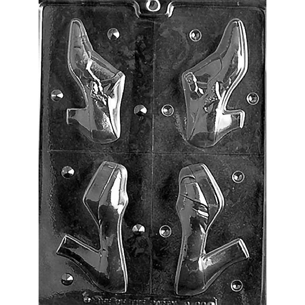 Clear plastic chocolate mold showing four cavities that form two different 3D women’s high heel shoes, with paired halves for each shoe design.