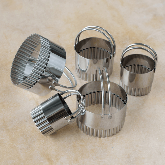 Five fluted biscuit cutters displayed on a countertop, showing different sizes.