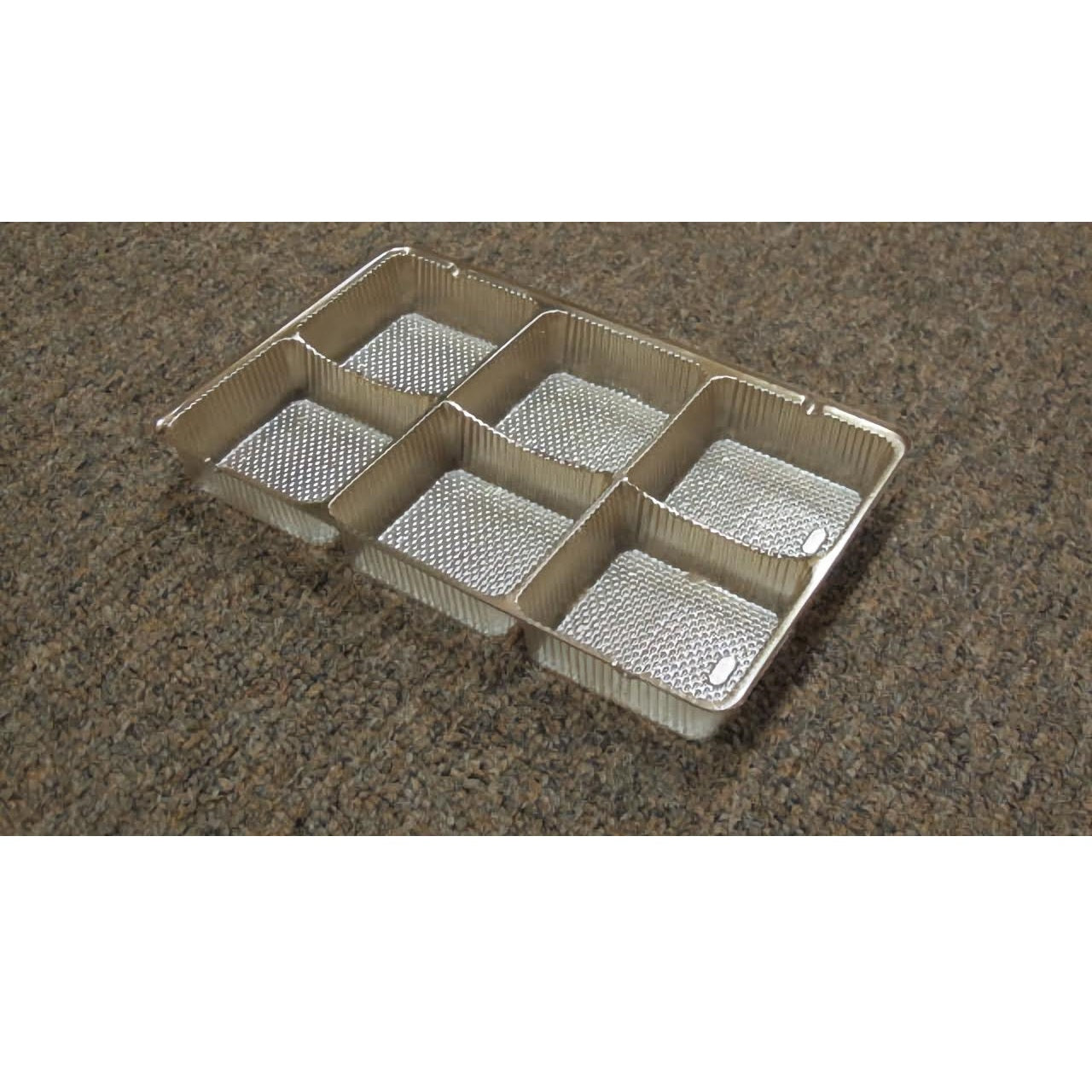 The image displays a six-cavity gold insert typically used in candy boxes. Each cavity is compartmentalized to hold individual confections, such as chocolates or truffles, ensuring they are separated and presented neatly.