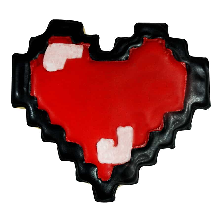 Decorated pixelated heart cookie with red icing, black edging, and white pixel details, resembling a classic video game heart.