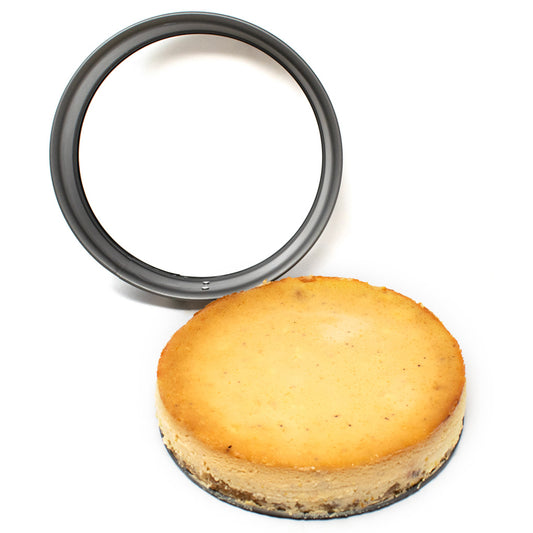 Black springform pan ring positioned behind a round golden cheesecake removed from the pan and resting on its removable base.