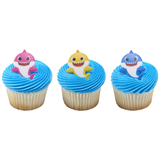 Three cupcakes with blue frosting, each topped with a Baby Shark-themed cupcake ring featuring Mommy Shark, Daddy Shark, and Baby Shark.