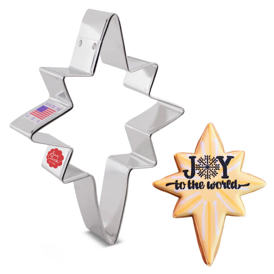 Bethlehem Star cookie cutter next to a decorated cookie with 'Joy to the World' written on it.