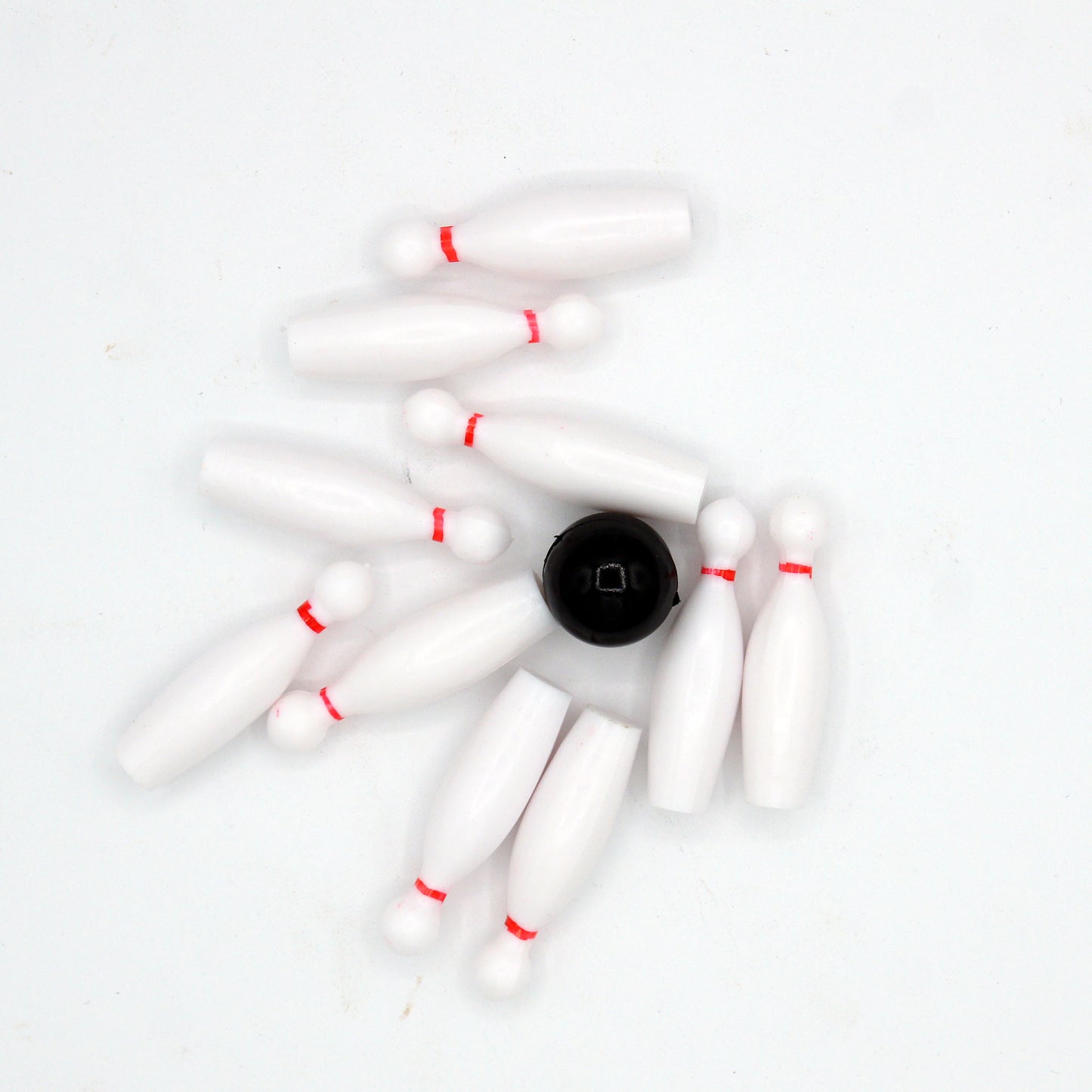 Bowling cake toppers scattered with the black ball in the center after a strike.