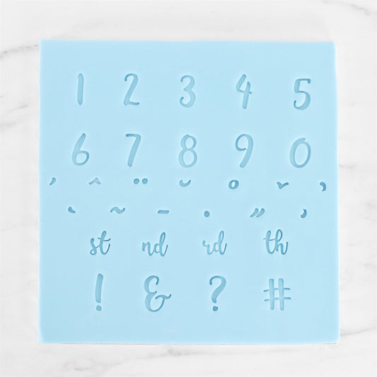 Close-up of number and punctuation impressions made using PME Fun Fonts stamp set on blue template.