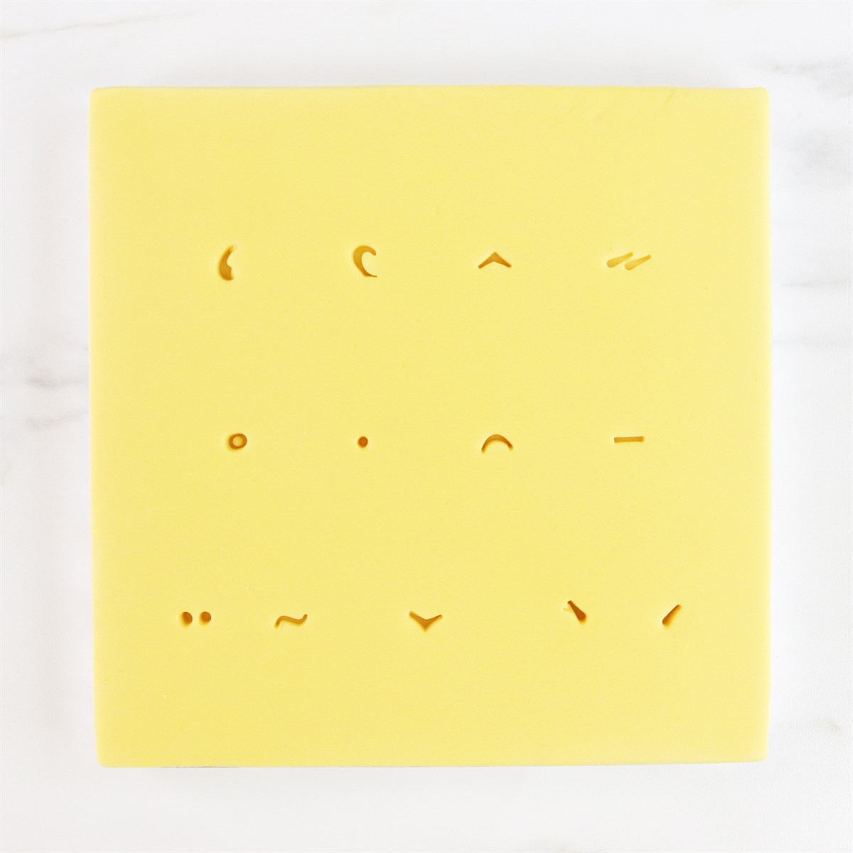Close-up of yellow stamp sheet with accent marks for multilingual cake decorating using PME Fun Fonts Collection 2.