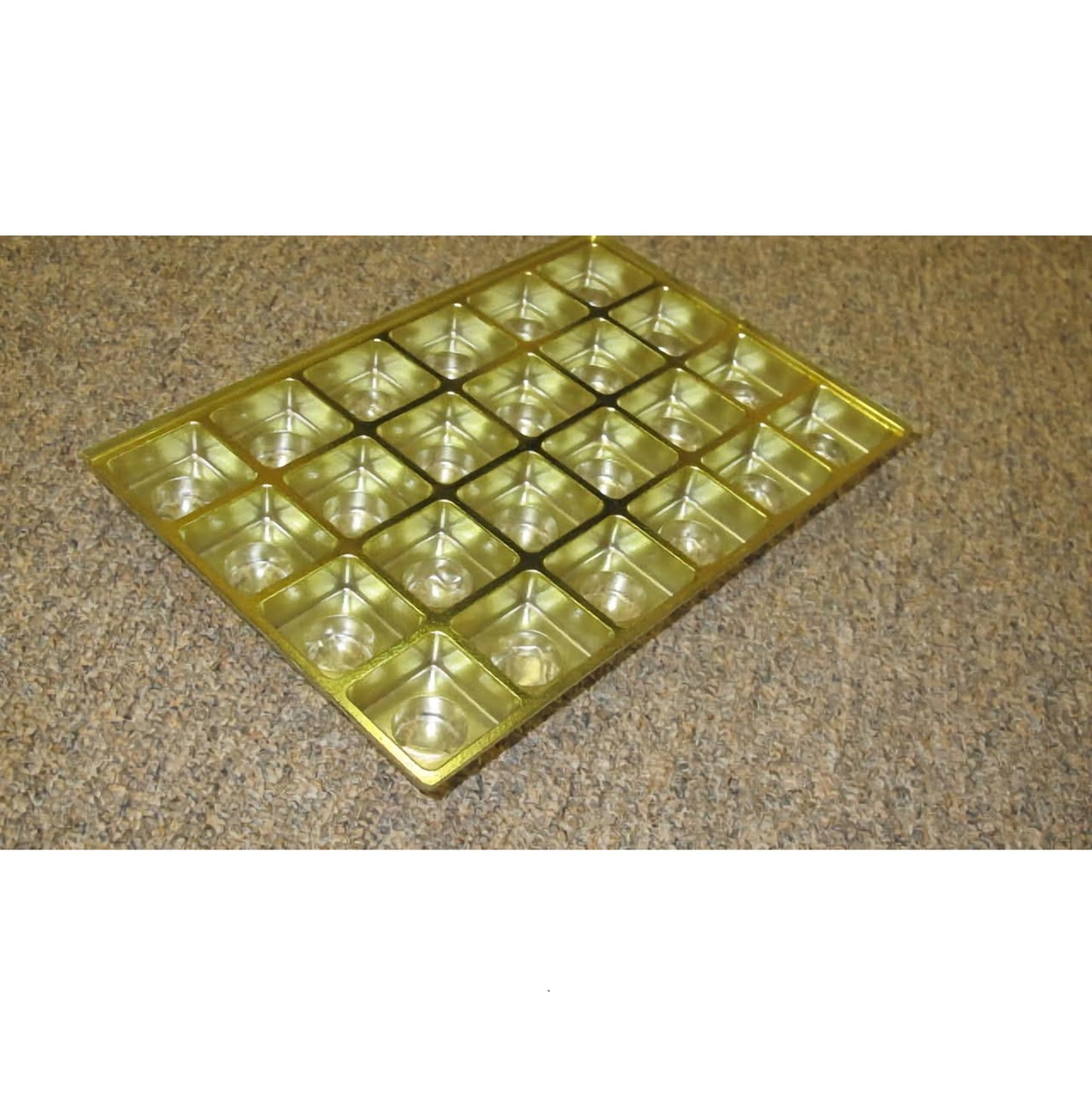 The image displays a gold, one-pound candy box insert with multiple small square cavities, each designed to hold a single piece of candy or chocolate. The cavities have a geometric indentation that adds a decorative touch to the presentation of the confectioneries.