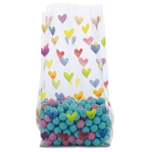 A cellophane treat bag adorned with a colorful array of watercolor-style hearts in shades of blue, yellow, pink, and purple, partially filled with candy to showcase the playful design.