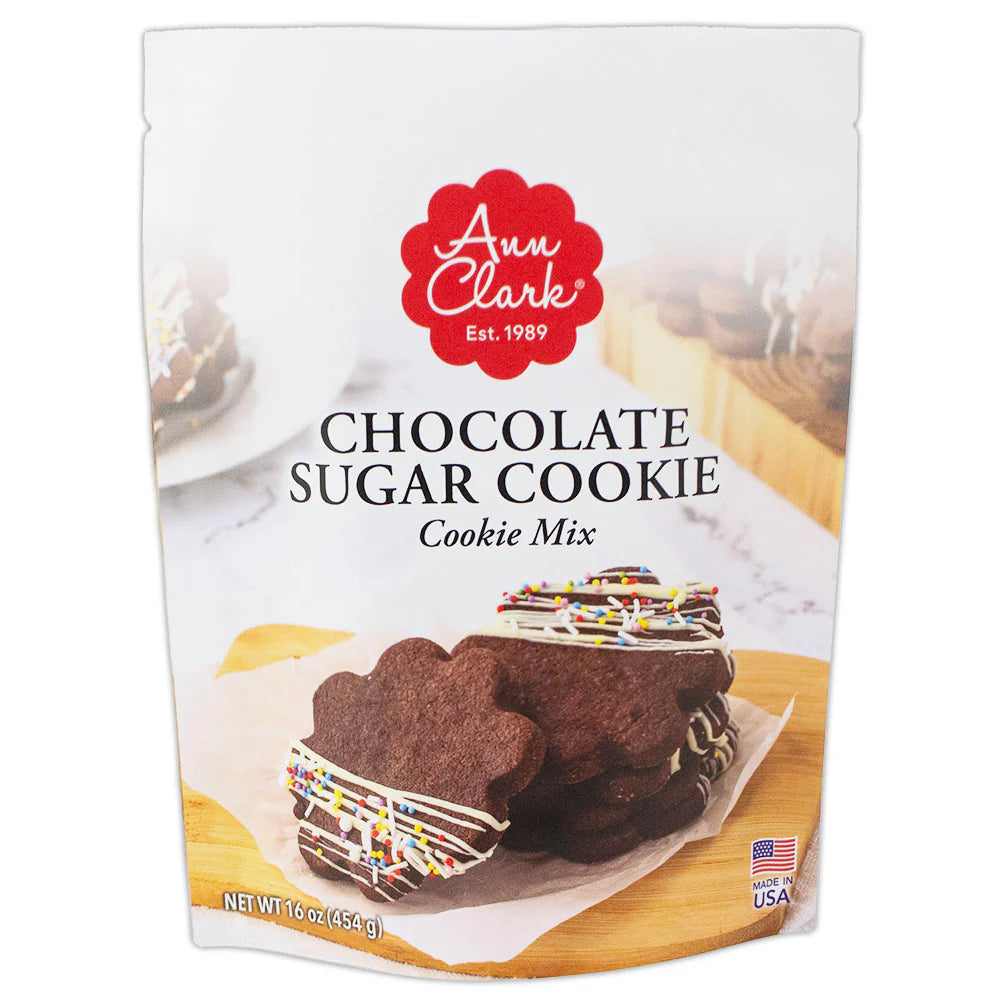 Front of Ann Clark Chocolate Sugar Cookie Mix package featuring chocolate cookies decorated with white drizzle and colorful sprinkles.