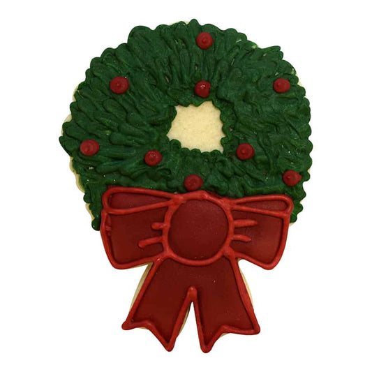 Christmas wreath cookie iced in deep green with small red ornament dots and a large red bow at the base; open center.