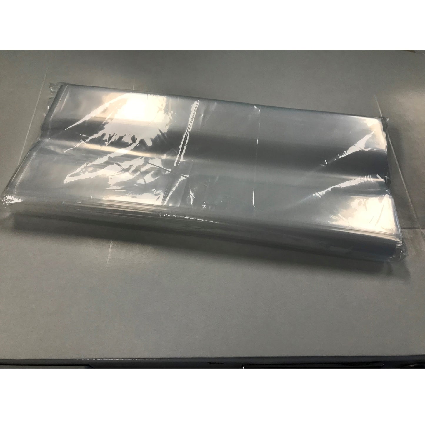 The photo displays a stack of clear poly bags with 5 x 3 x 12-inch dimensions. These 2 Mil gusseted bags have a shiny appearance, suitable for a variety of packaging needs.