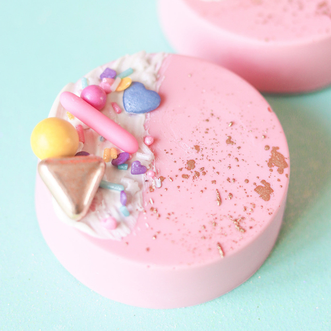 Chocolate-covered dessert disc tinted with Colour Mill Blush, decorated with colorful sprinkles, metallic accents, and textured white detail