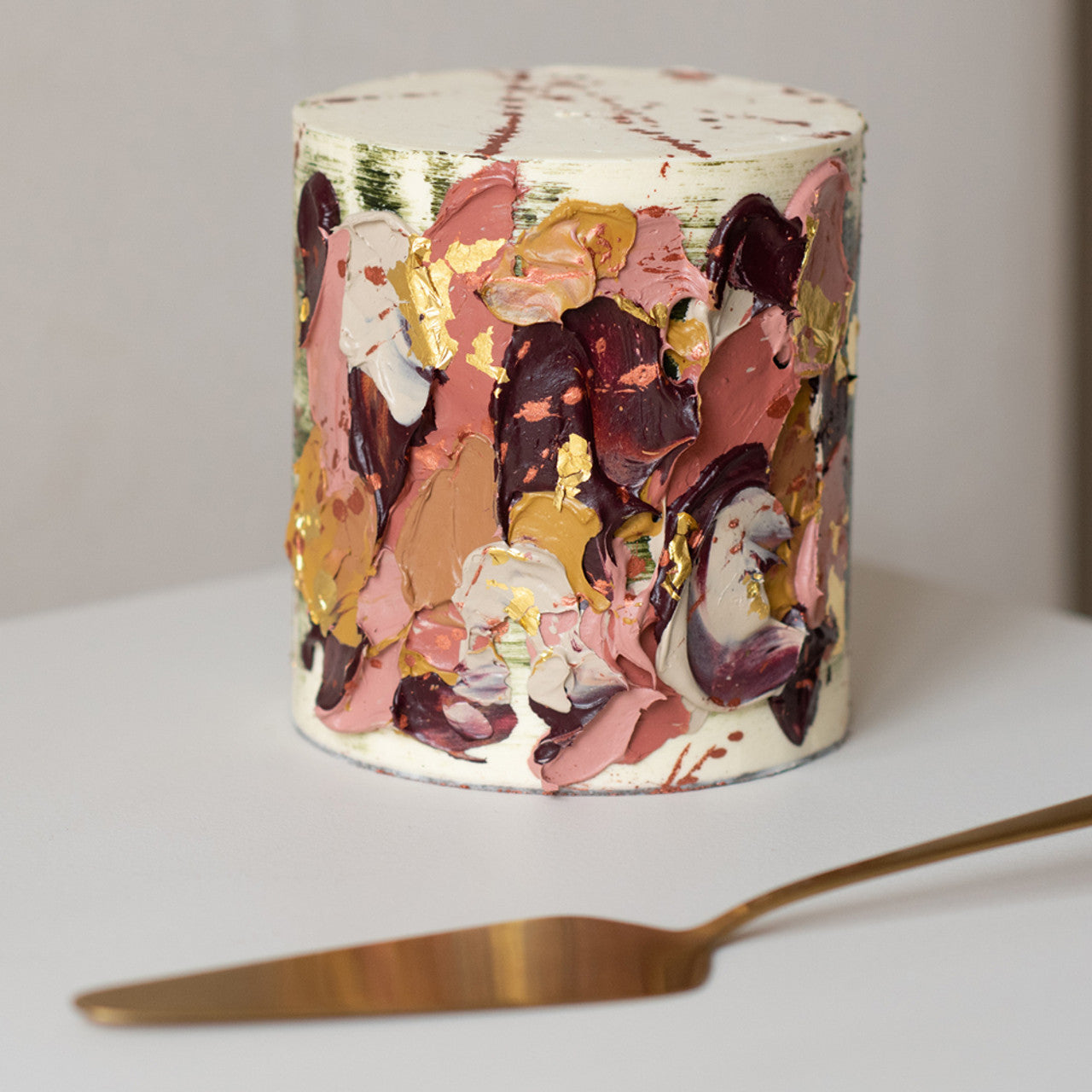 Textured buttercream cake with abstract palette knife design using Colour Mill Caramel and other shades, accented with gold leaf