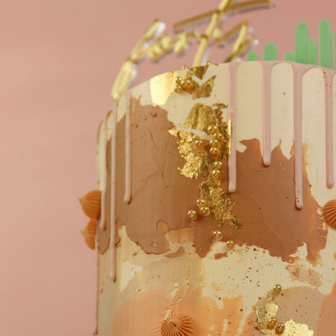 Layered buttercream cake decorated with Colour Mill Clay food coloring, pink and cream tones, gold leaf, and piped rosettes