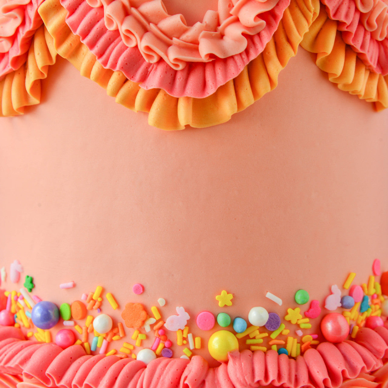 Cake decorated with buttercream ruffles and sprinkles in tropical tones using Colour Mill Coral.