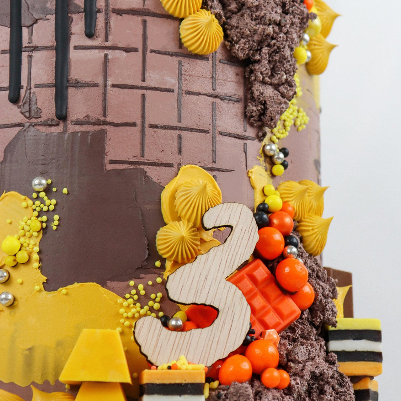 Autumn-themed cake with mustard yellow frosting accents, chocolate textures, and orange decorations using Colour Mill Mustard