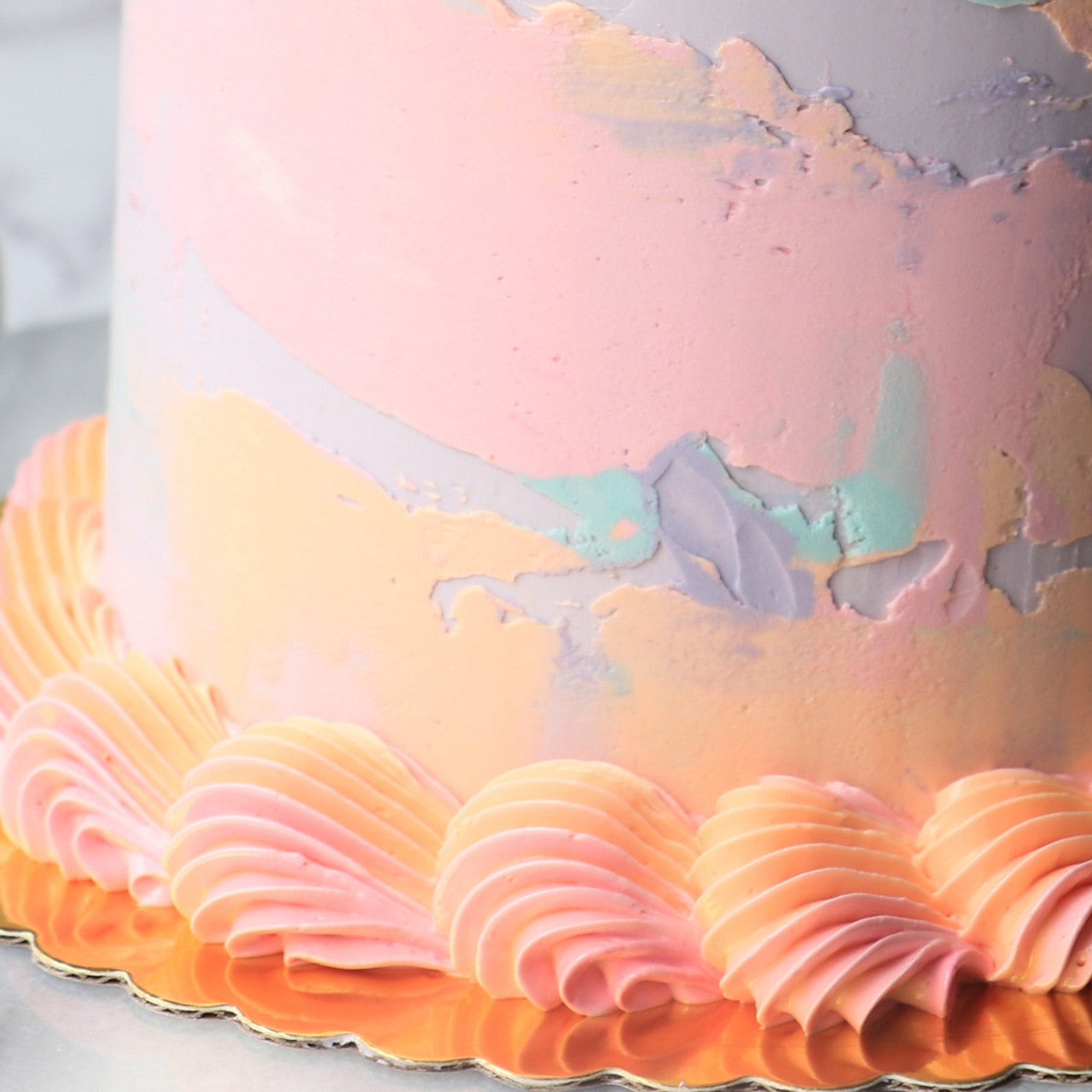 Cake decorated with pastel buttercream in shades of peach, pink, lavender, and mint using Colour Mill oil-based colors