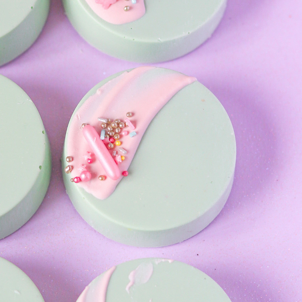 Round pastel green confections with pink chocolate drizzle and colorful sprinkles, decorated using Colour Mill Tiffany food coloring