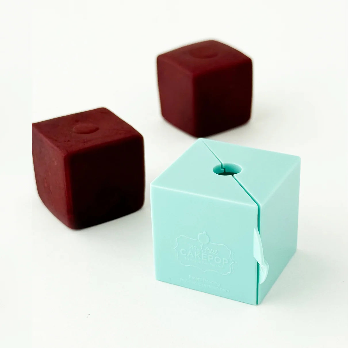 Cube cake pop mold shown alongside finished red velvet cube-shaped cake pops, demonstrating mold results and sharp edges.