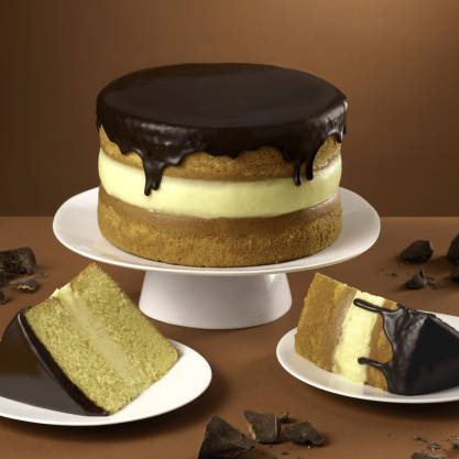 Layered cake with chocolate ganache on a white plate against a brown background
