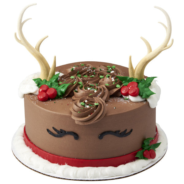 Reindeer-themed holiday cake with chocolate frosting, holly decorations, and deer antler toppers.