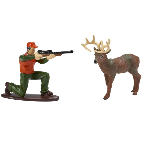 Close-up of two plastic cake toppers: a kneeling hunter with a rifle and a standing buck with antlers, shown against a white background.