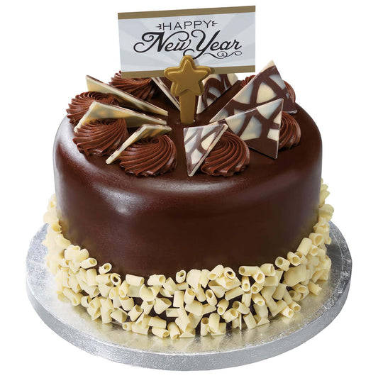 A New Year's themed chocolate cake adorned with Diablo Triangle Chocolate Decorations in dark and white marbled chocolate, surrounded by white chocolate curls and topped with a 'Happy New Year' sign.
