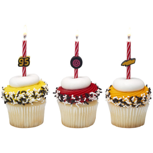 Three cupcakes decorated with red and yellow frosting, each topped with a Cars birthday candle featuring Lightning McQueen’s number, a tire, or a lightning bolt.