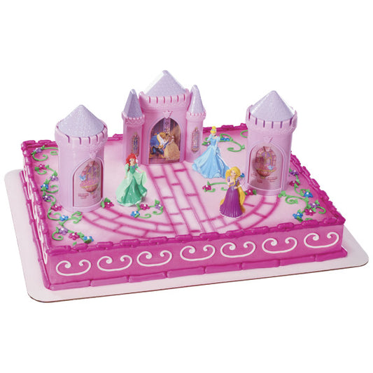 A rectangular cake decorated with the Disney Princess Castle Signature DecoSet®, featuring the castle, turrets, and princess figurines on a pink royal-themed design.