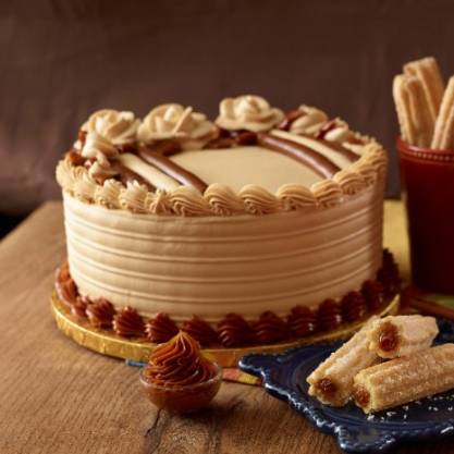 Decorative cake with cream and dulche de leche on a wooden table