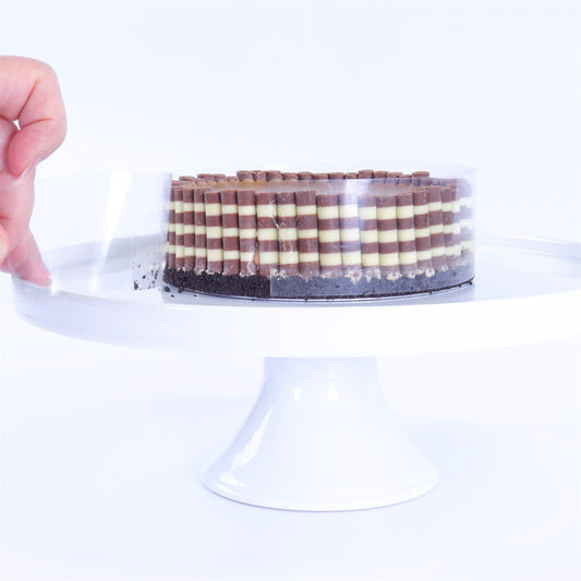 Hand peeling PME acetate roll from decorated cake with striped chocolate sticks on cake stand.