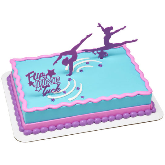 Sheet cake decorated with blue frosting, pink and purple borders, and purple gymnastics toppers including gymnasts and a Flip Jump Tuck sign.