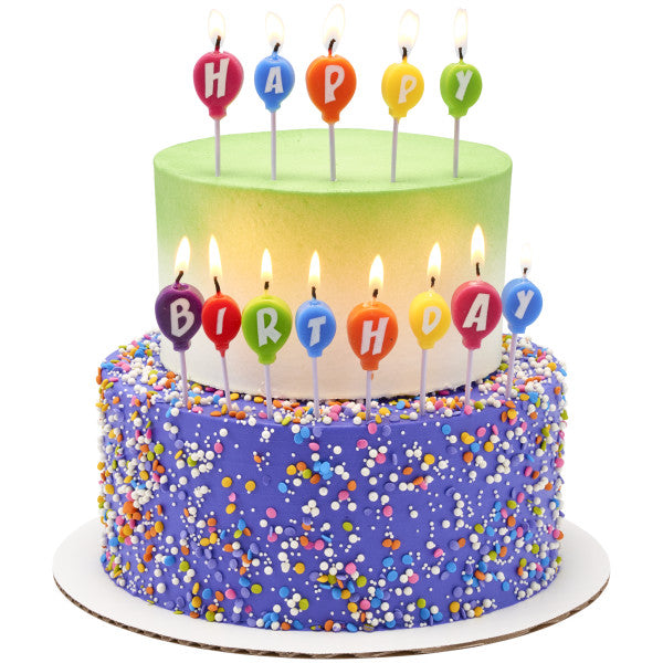 Tiered birthday cake decorated with lit balloon-shaped candles spelling "HAPPY BIRTHDAY" on green and purple frosted layers