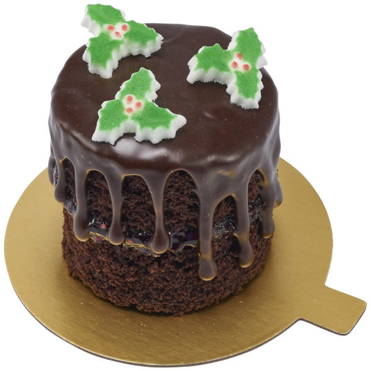Edible pressed sugar cake decorations shaped like holly leaves on a chocolate cake.