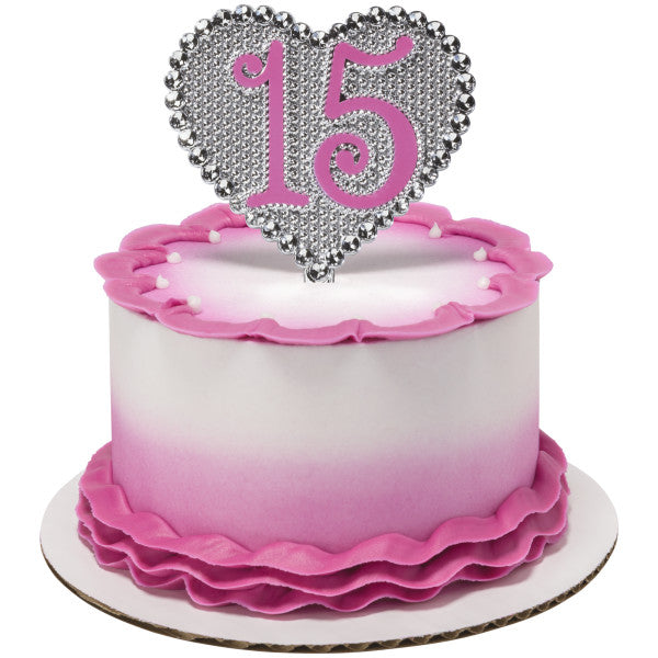 Pink ombre cake with ruffle fondant detailing topped with silver heart-shaped "15" Quinceañera cake topper.