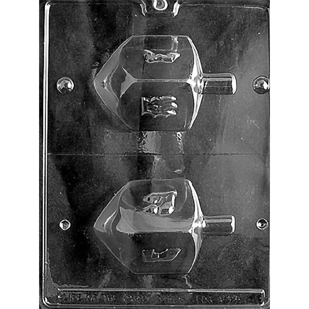Clear plastic 3D chocolate mold with two large dreidel-shaped halves, designed to form a detailed dreidel with raised Hebrew letter panels, shown on a dark background.