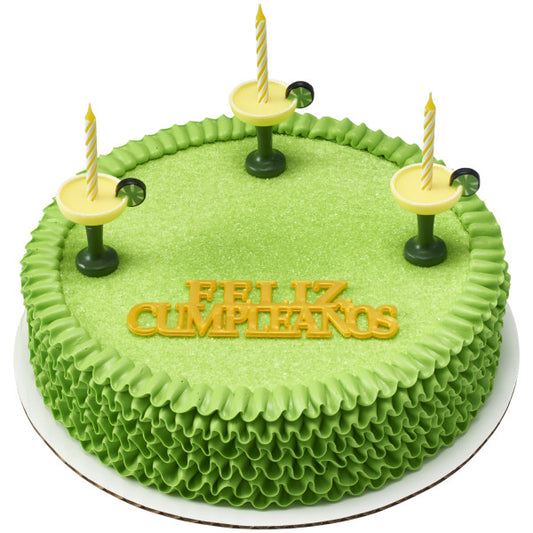 Green birthday cake topped with yellow spiral candles in margarita glass holders and a "Feliz Cumpleaños" topper.