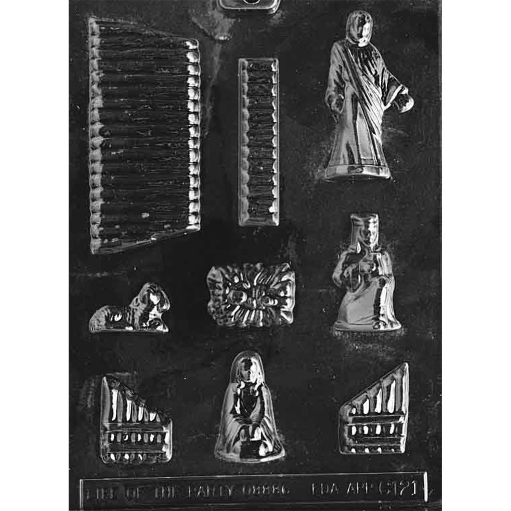 Clear plastic chocolate mold with multiple nativity-themed cavities, including Mary, Joseph, baby Jesus, a manger crib, and textured scene panels; shown on a dark background.