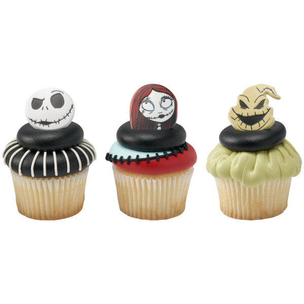 Three cupcakes topped with Nightmare Before Christmas character rings, featuring Jack Skellington, Sally, and Oogie Boogie on black, red, and green themed frosting designs.