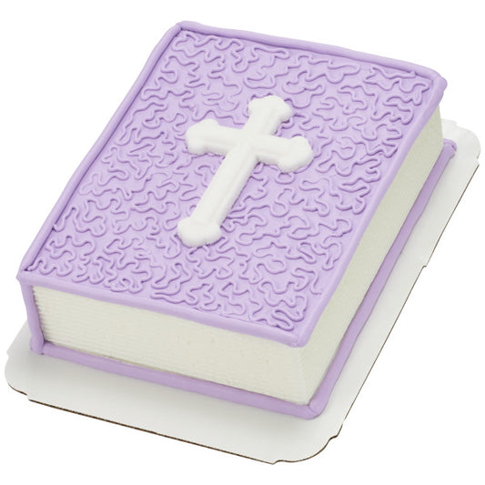 Religious-themed cake decorated with a purple textured top and a white cross-shaped sugar decoration as the centerpiece.