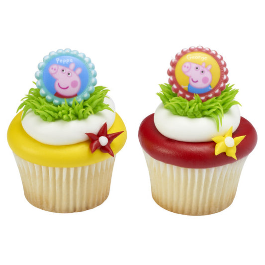 Two cupcakes topped with Peppa Pig and George rings, decorated with fondant flowers and grassy green frosting.