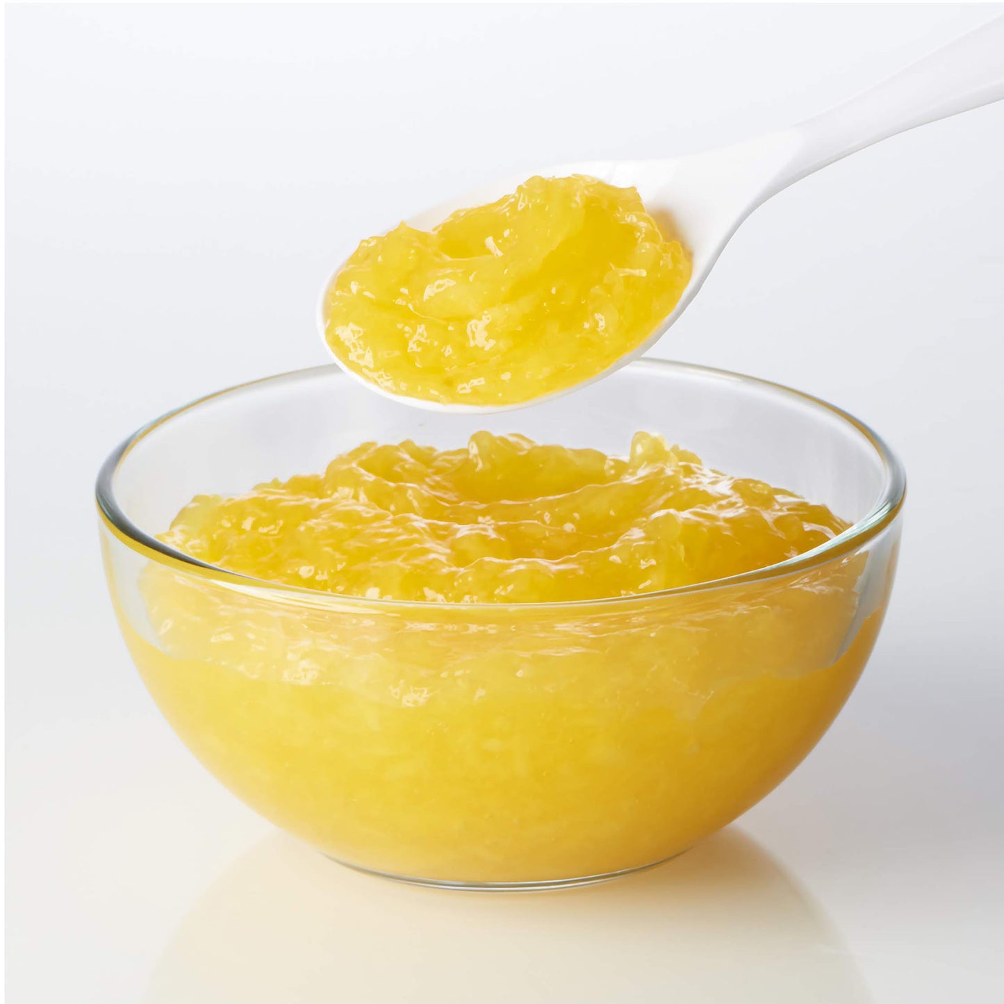 Bowl of pineapple cake filling with spoonful lifted above, showing bright yellow crushed pineapple texture.