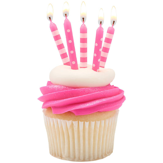 Pink striped and polka dot birthday candles on a cupcake with pink frosting. Candles are lit and placed in a white frosted cupcake.