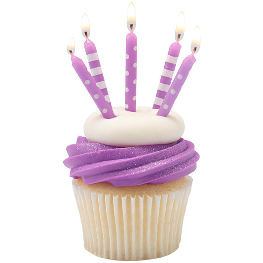 Cupcake with purple frosting topped with five lit birthday candles in purple and white stripes and polka dots.
