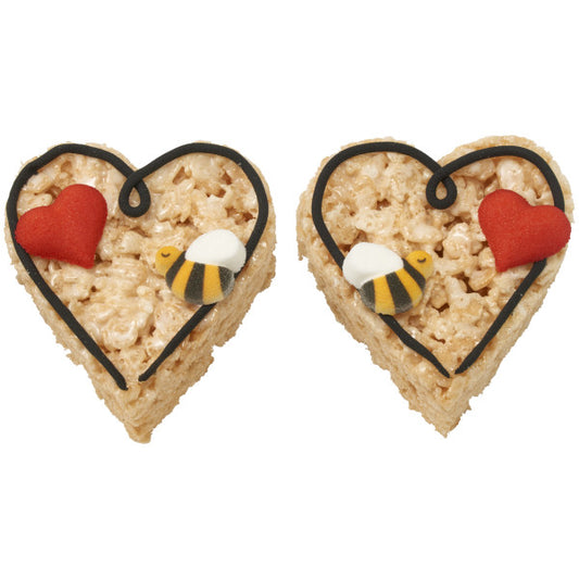 Two heart-shaped treats with red hearts and yellow bees on a heart shaped rice krispy bar.