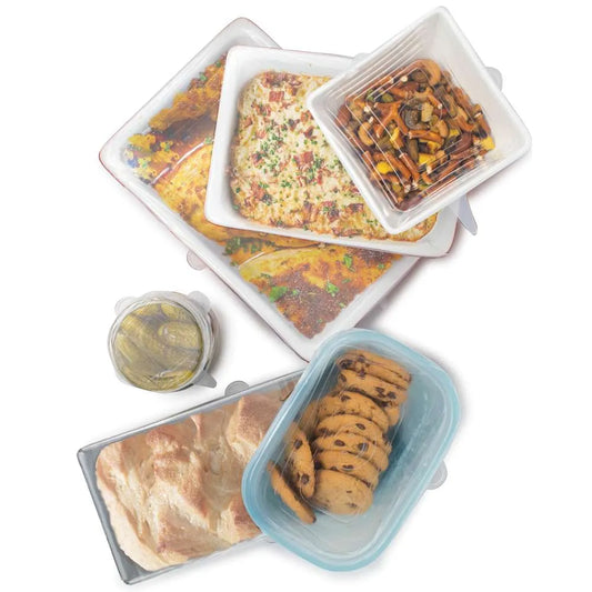 Silicone food covers stretched over dishes, jars, and containers filled with food, demonstrating their secure fit and transparency.